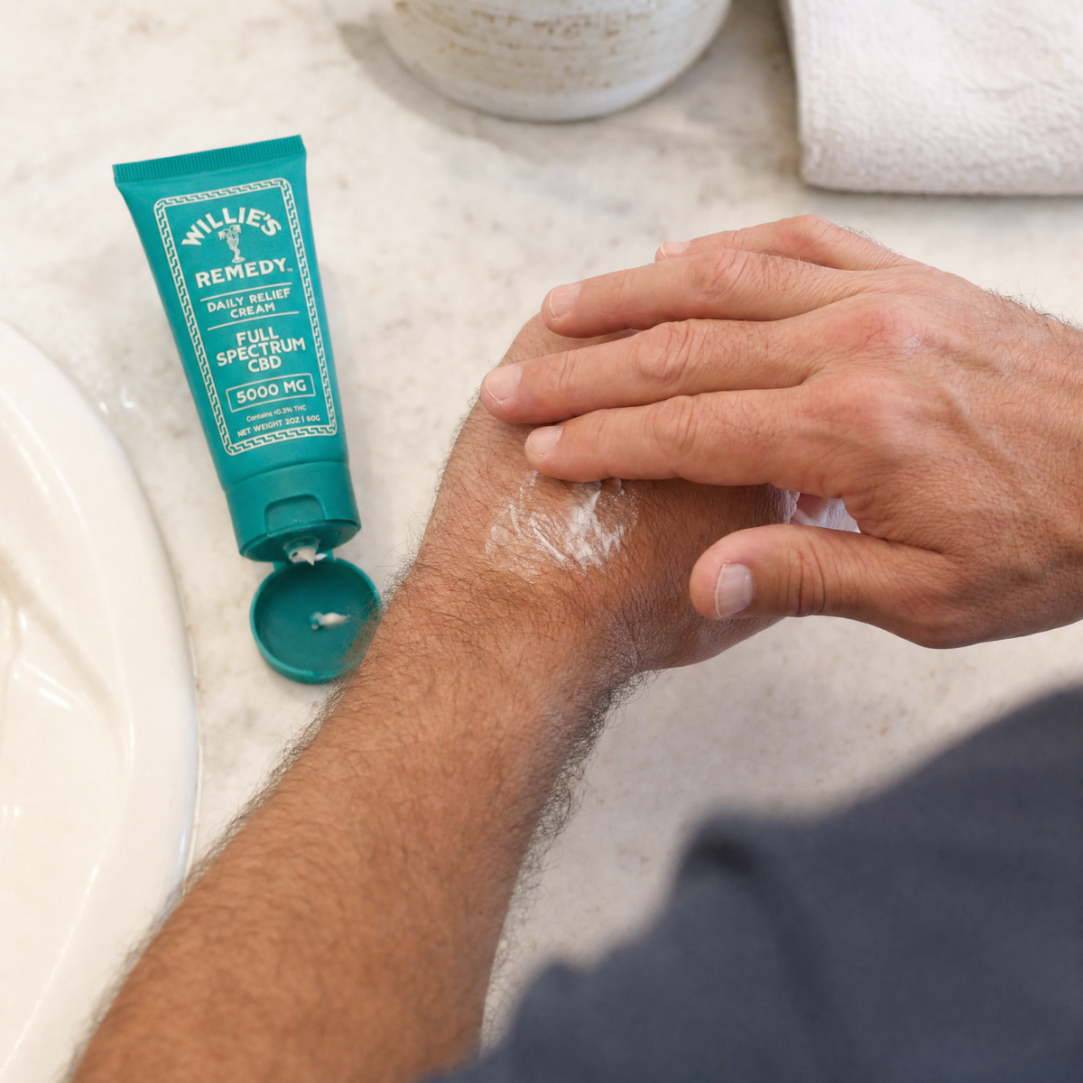 Person rubbing Willie's Remedy Daily Relief Cream into their hands