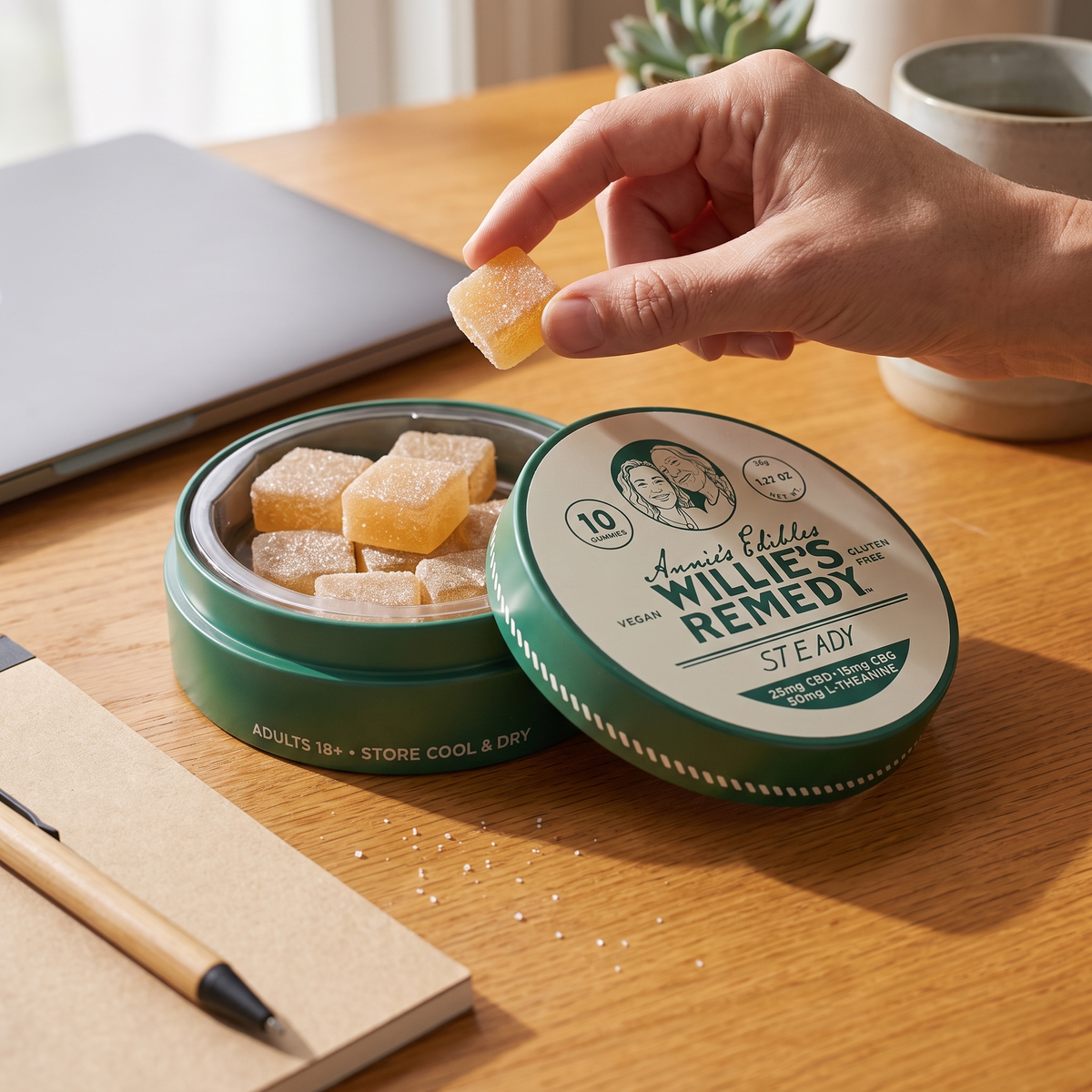 Hand taking a Steady CBD gummy from the tin at a desk