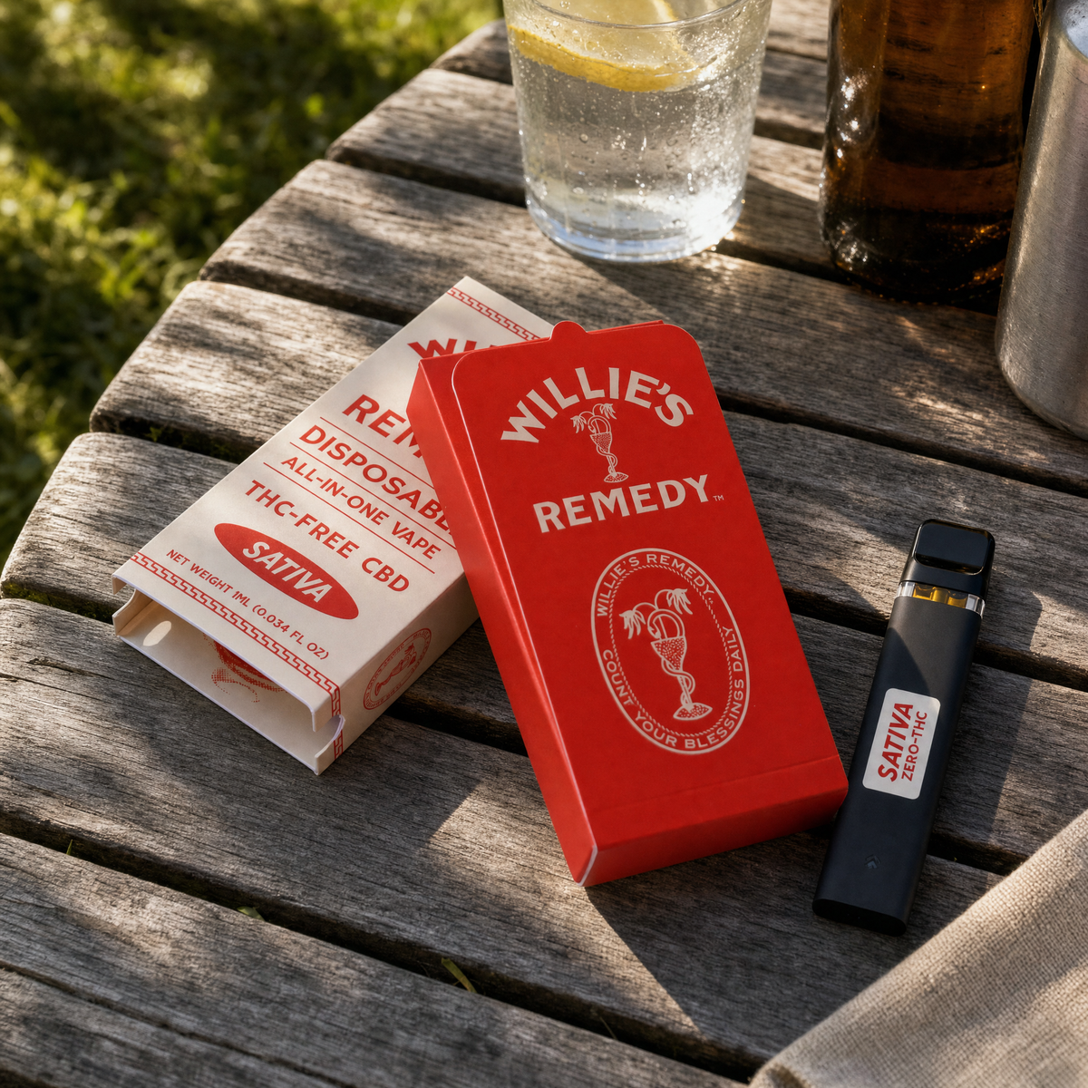 Willie's Remedy THC-Free Sativa vape and box on a sunny outdoor table with drinks