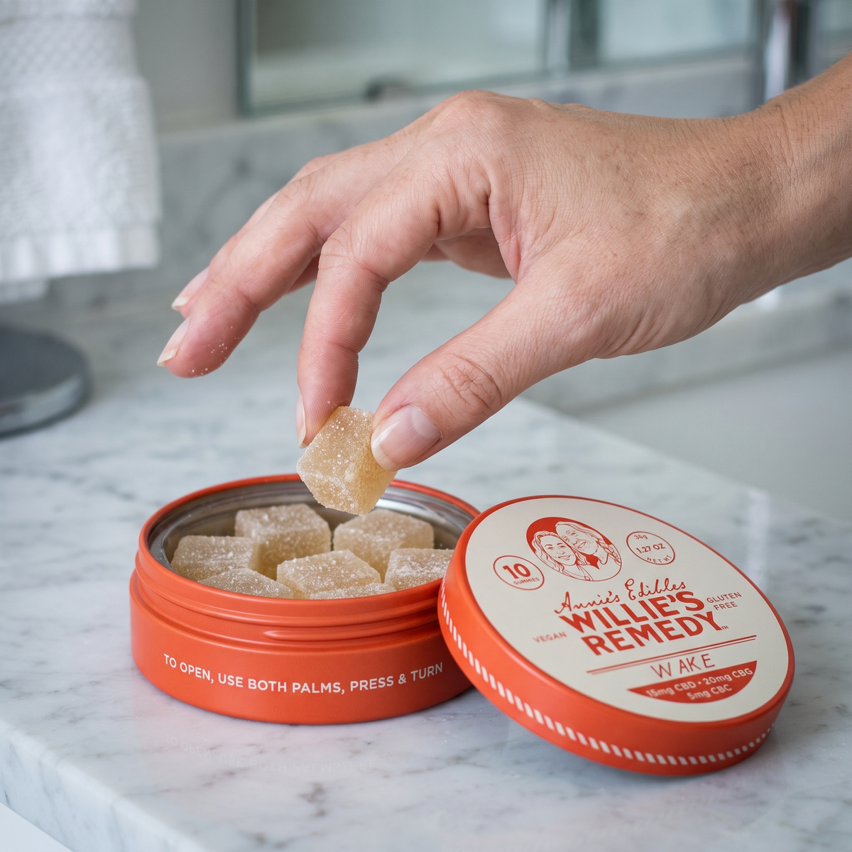 Hand taking a Wake CBD gummy from the tin