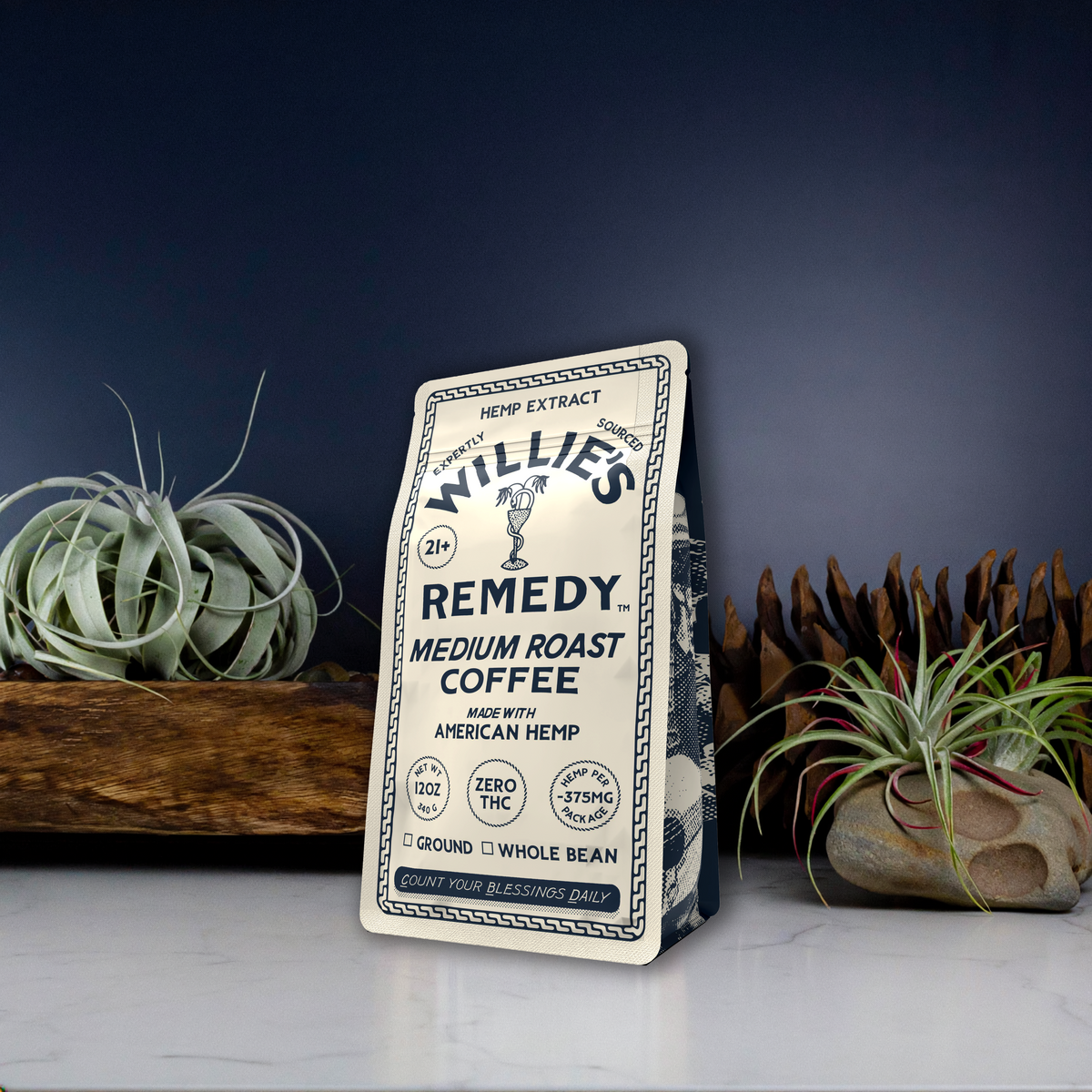 Willie's Remedy CBD Medium Roast Whole Bean Coffee bag among desert plants on a dark background