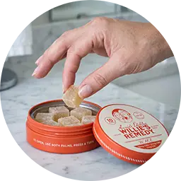 Hand taking a gummy from a tin of Annie's Edibles x Willie's Remedy CBD gummies